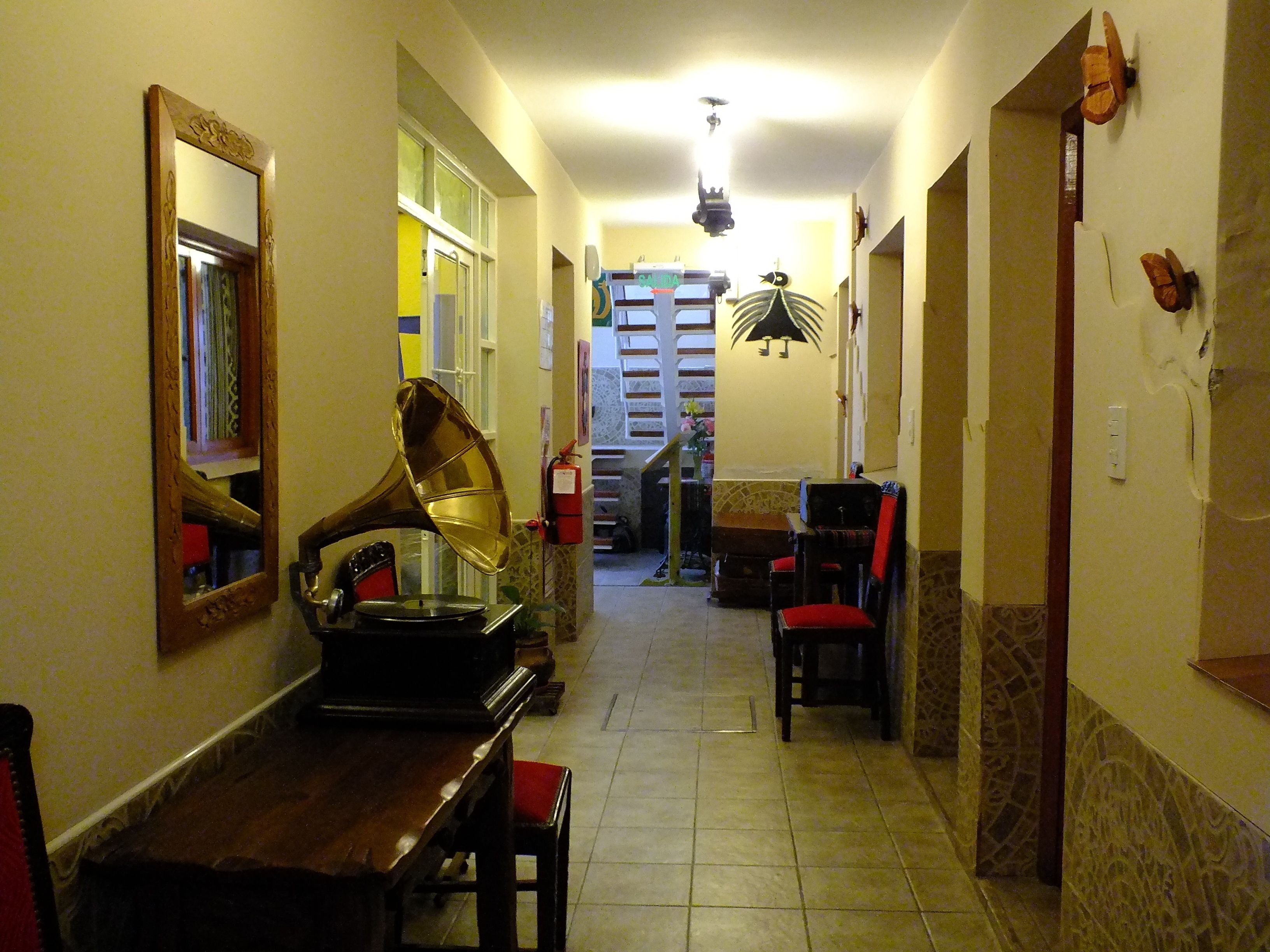 Un pasillo con un piano, sillas, un espejo y una escalera que lleva a un piso superior.