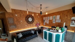 Un área de recepción con un sofá, un escritorio, un reloj y certificados enmarcados en la pared.