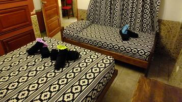 Un dormitorio con dos camas, un armario de madera y una cortina estampada.