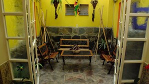 Un patio acogedor con pared de piedra, muebles de madera y jardineras colgantes.
