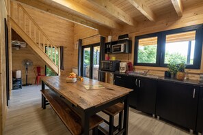 Um interior de madeira com cozinha, mesa de jantar e escada.