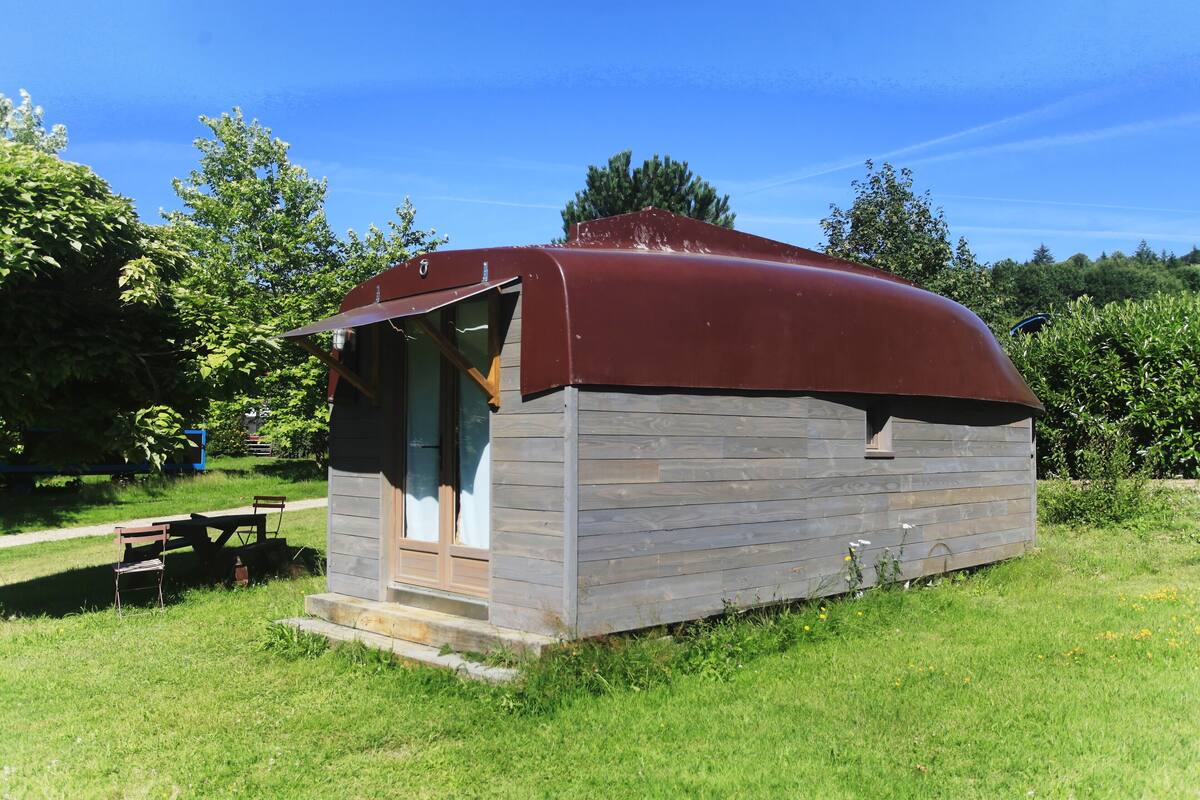 Eine kleine Holzhütte mit rotem Dach, Tür und Fenster.