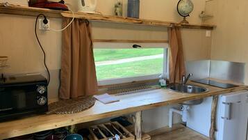 A compact kitchen with a window, a microwave, a sink, and a refrigerator.