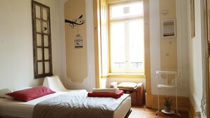 A bedroom with a bed, a window, a chair, and a small table. - Refuge in Santa Marta Hostel (Lisbon)