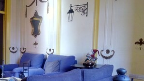 A room with a blue sofa, a wooden bench, a table with a lantern, and decorative wall elements. - Refuge in Santa Marta Hostel (Lisbon)