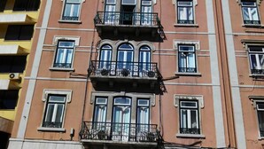 A multi-story building with balconies, a storefront labeled "CERIMÓNIA," and a clear blue sky in the background. - Refuge in Santa Marta Hostel (Lisbon)