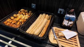 Ein Buffet mit verschiedenen Backwaren, darunter Gebäck und Brot, sowie ein Toaster.