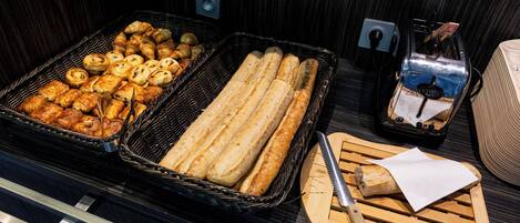 A buffet with various baked goods, including pastries and bread, and a toaster.