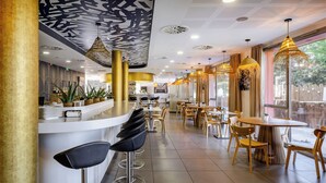 Interior moderno de restaurante com área de bar, assentos e elementos decorativos no teto.