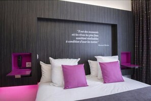 A modern bedroom with a large bed, white and purple pillows, and a quote on the wall. - Akena Nantes Atlantis (Saint-Herblain)
