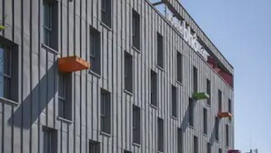 Um edifício moderno com fachada vermelha e diversos espaços de estar ao ar livre, com design colorido e original.