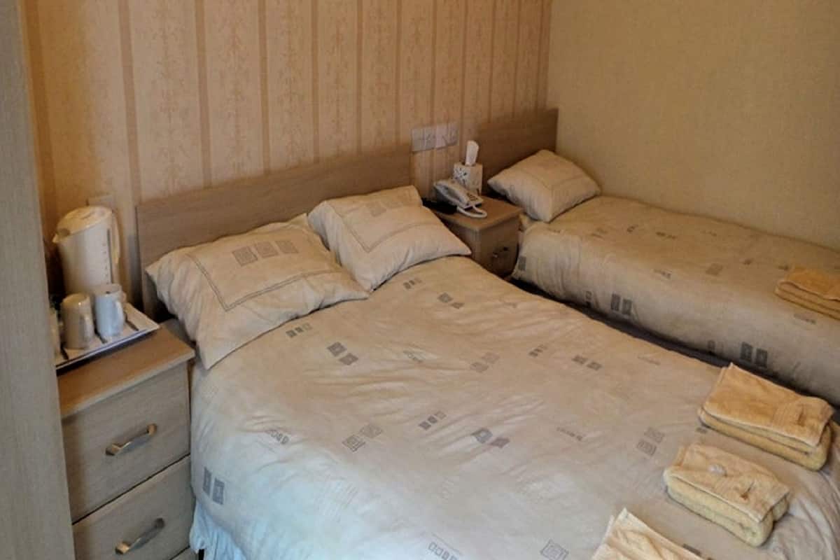 Ein Hotelzimmer mit zwei Betten, einem Nachttisch mit Telefon und einem kleinen Tisch mit Kaffeemaschine und Taschentuchbox.