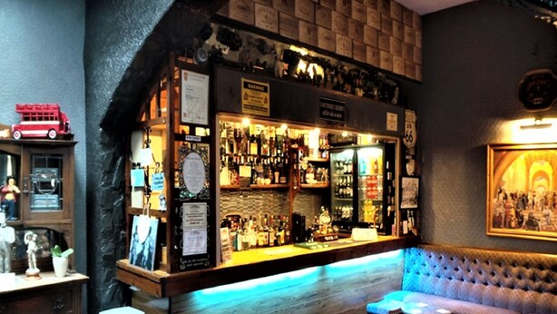 A bar area with a wooden counter, shelves of bottles, and a seating area with stools. - Parkfield Hotel (Blackpool)