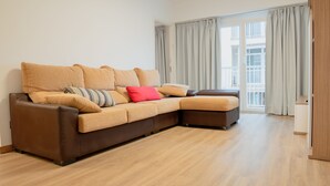 Una sala moderna con un sofá modular, un pequeño reposapiés y piso de madera.