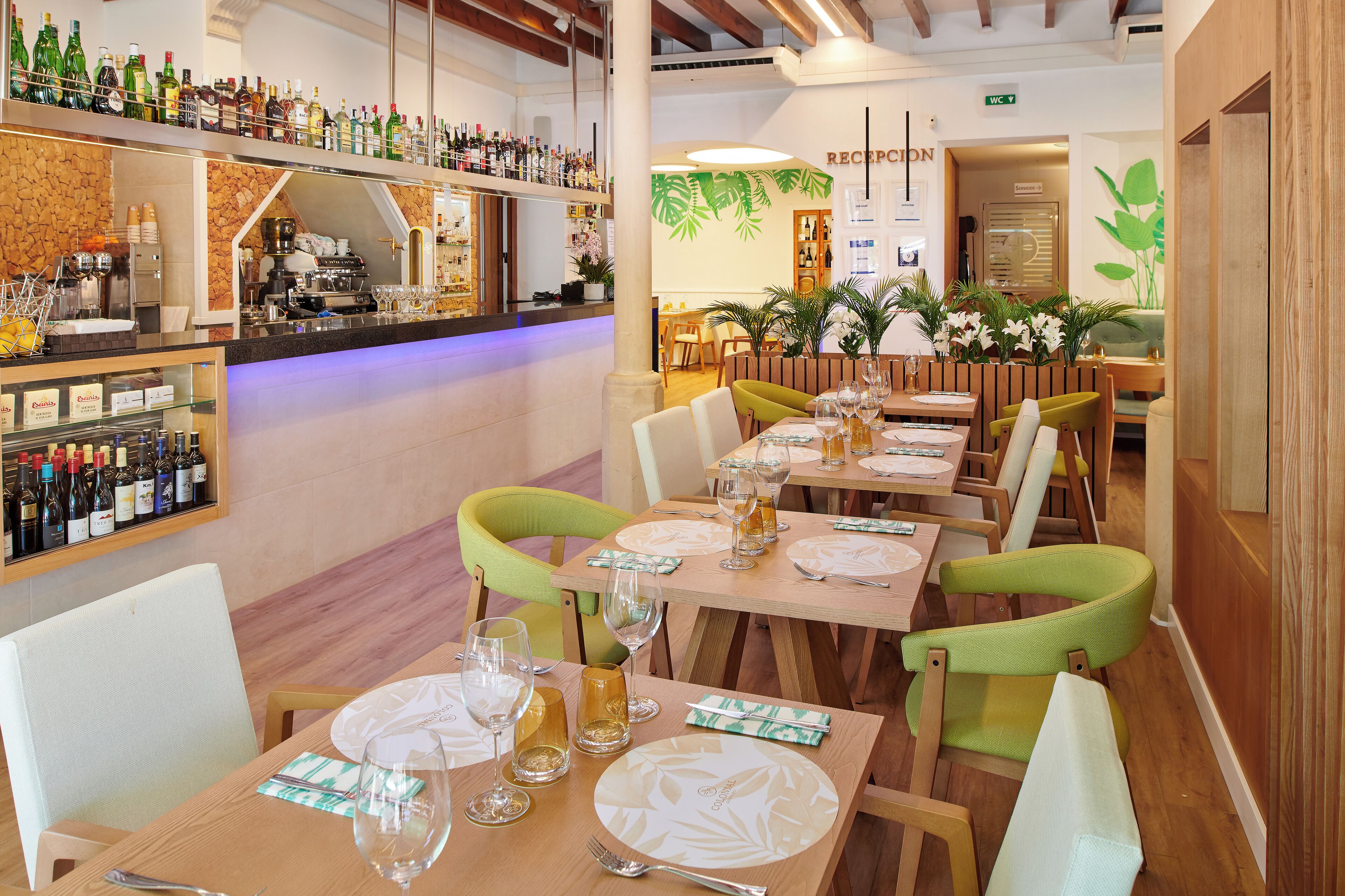 Een restaurant met meerdere eettafels, stoelen en een bar voorzien van verschillende flessen.