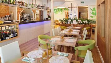 Een restaurant met meerdere eettafels, stoelen en een bar voorzien van verschillende flessen.