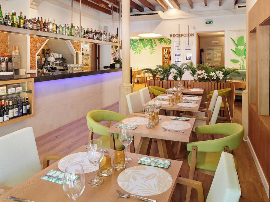 Een restaurant met meerdere eettafels, stoelen en een bar voorzien van verschillende flessen.