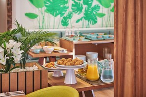 A breakfast buffet with various dishes, a pitcher of orange juice, and a decorative plant. - Hotel Colonial (Ses Salines)