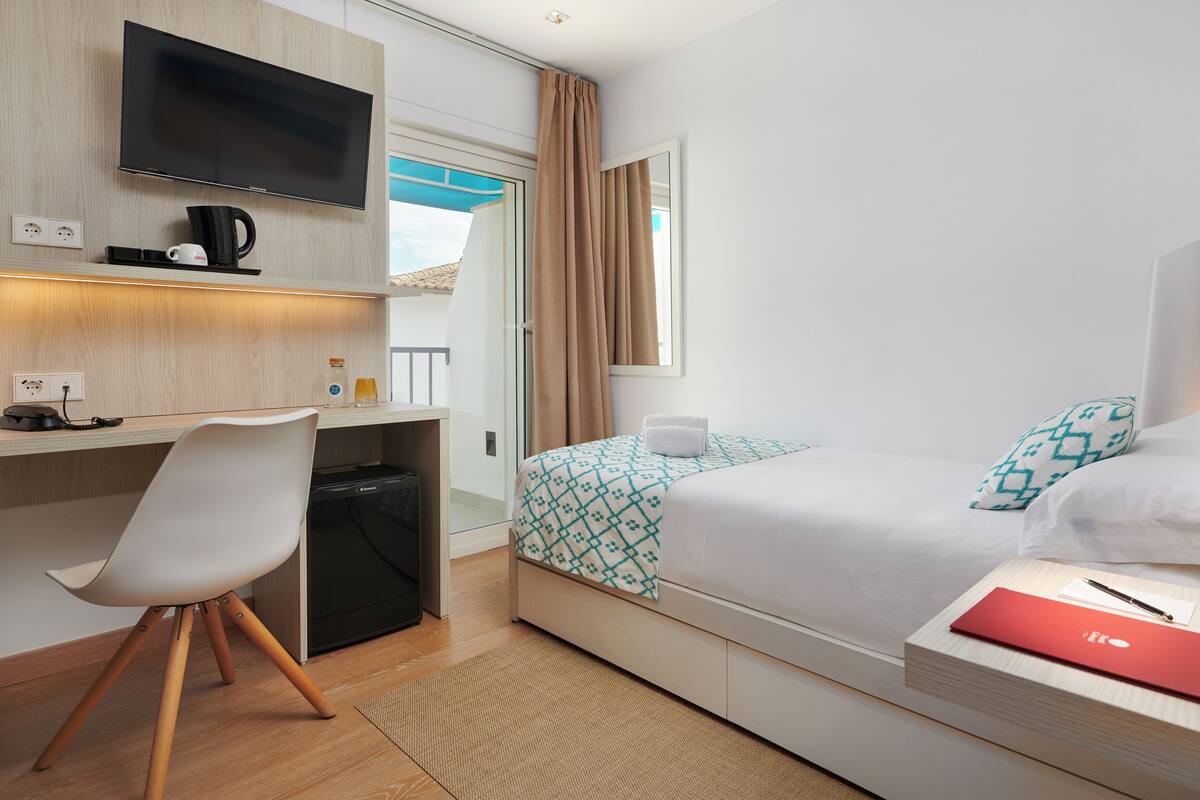 Habitación de hotel con cama, escritorio, silla y televisor.