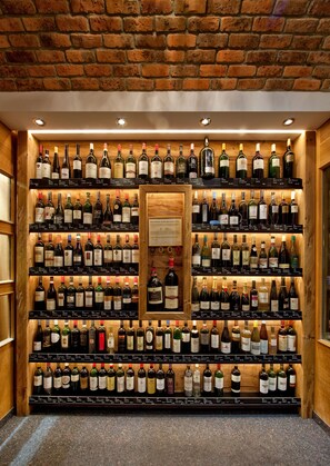 Une cave à vin dotée de plusieurs étagères remplies de bouteilles de vin, de murs en bois et d’une plaque commémorative au centre.