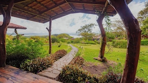 A covered wooden deck with a stone pathway leading to a lush green landscape. - Hotel Mystica (Santa Rosa)