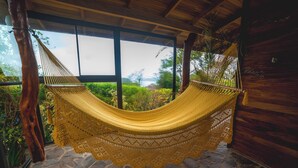 A hammock in a wooden room with stone flooring and large windows. - Hotel Mystica (Santa Rosa)
