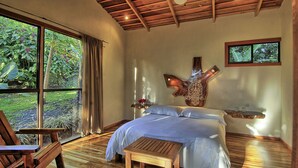 A bedroom with a large window, wooden furniture, and a unique wall art piece. - Hotel Mystica (Santa Rosa)