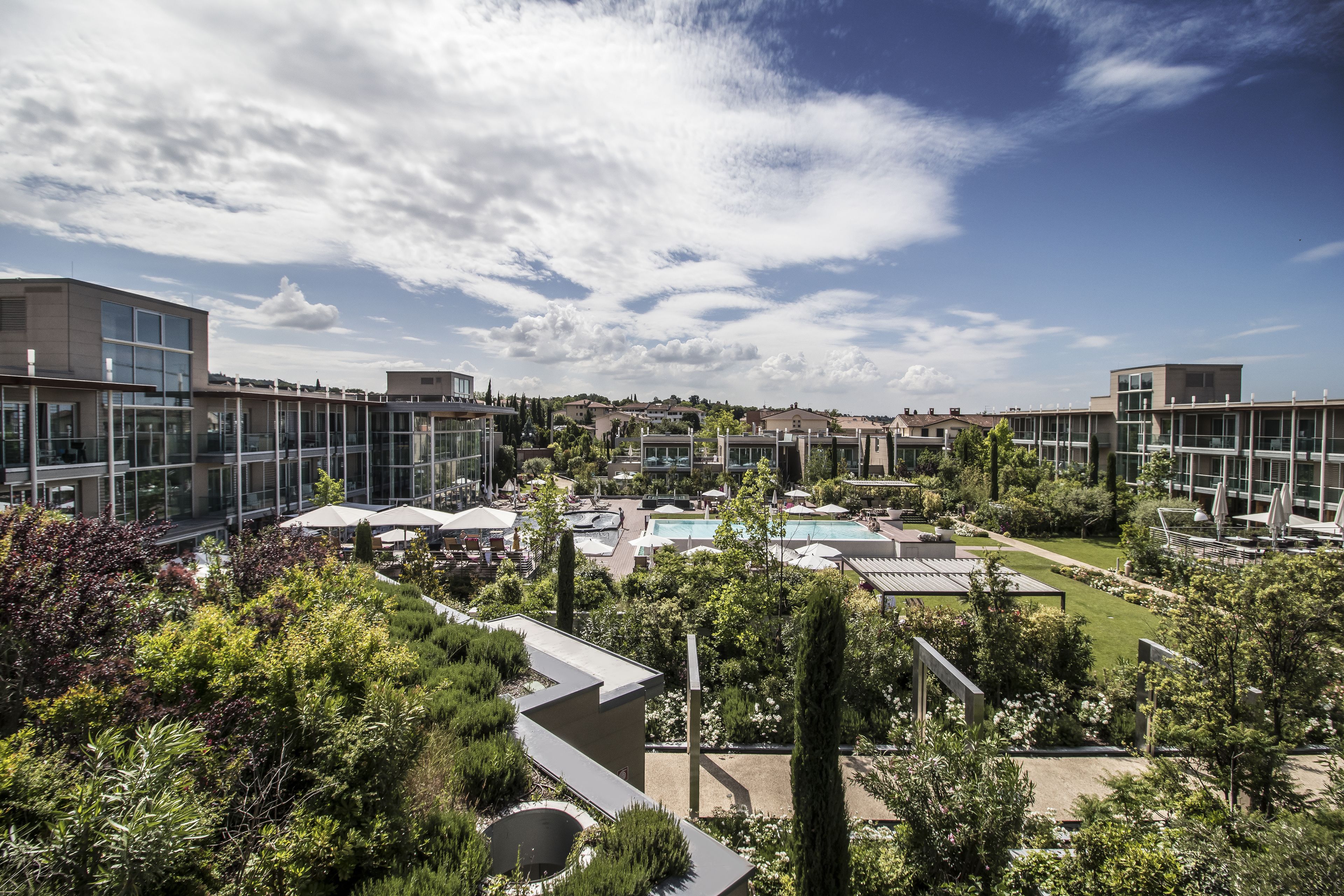 A modern hotel with a rooftop pool, lush greenery, and contemporary architecture.