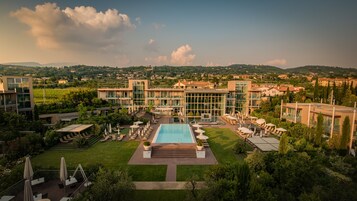 Un hotel moderno con piscina central, rodeado de exuberantes jardines y vistas al campo.
