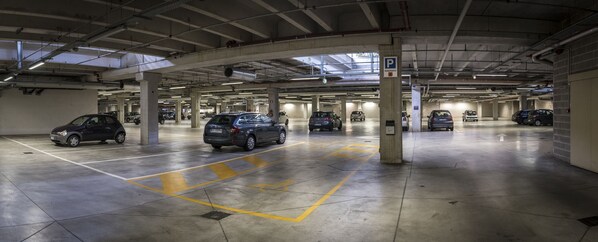A multi-level underground parking garage with concrete pillars, marked parking spaces, and a sign indicating reserved parking.