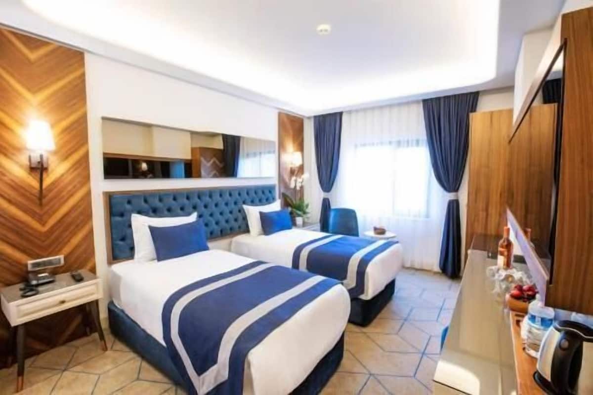 Habitació d'hotel amb dos llits, un escriptori, un minibar i una televisió.