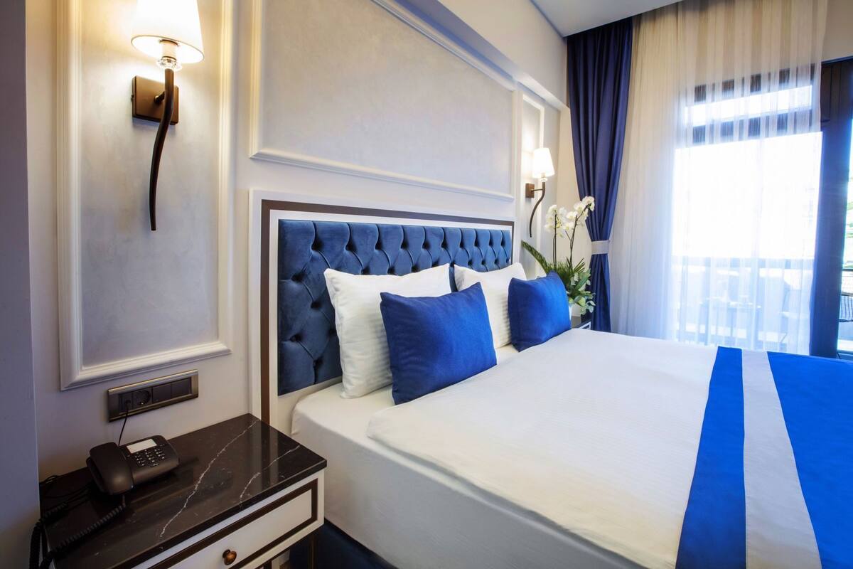 Una habitació d'hotel amb un llit gran, un telèfon a la nit i una taula de nit.