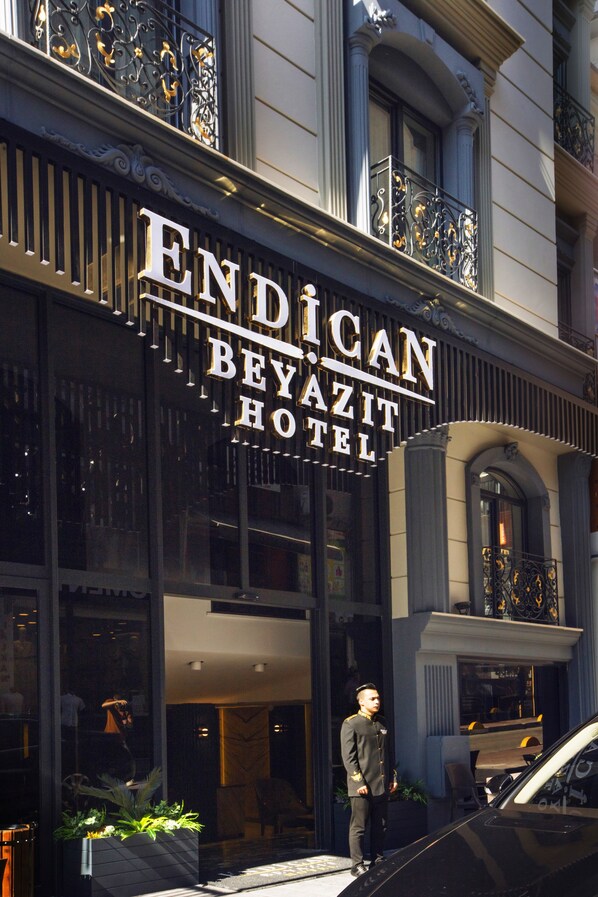 The exterior of the Endican Beyazit Hotel with a prominent sign, a black car parked in front, and a person standing near the entrance.