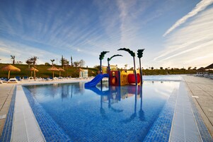 A swimming pool with a blue slide and a play structure.