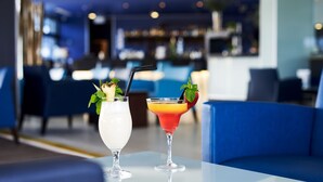 Two cocktails on a table in a modern bar setting with blue seating and a blurred background. - RR Alvor Baía Resort (Portimão)