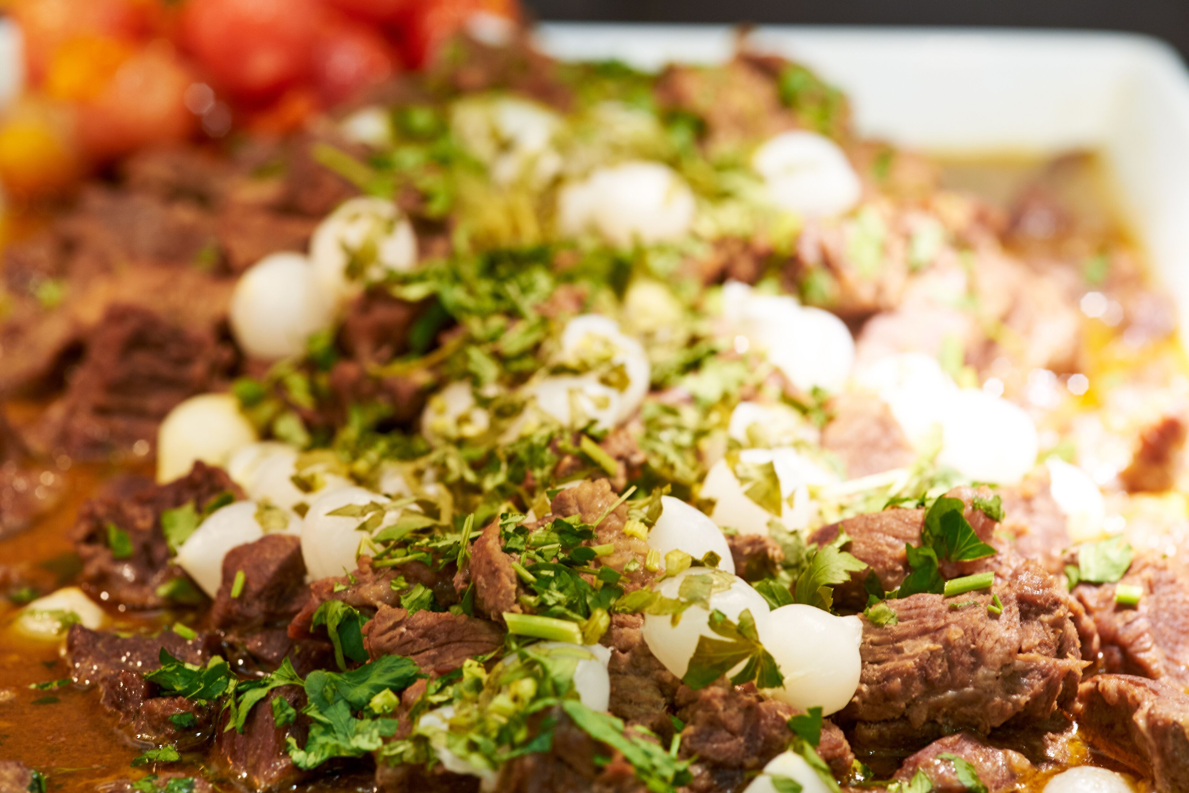 Une vue rapprochée d’un plat contenant de la viande, des œufs durs et des herbes hachées.