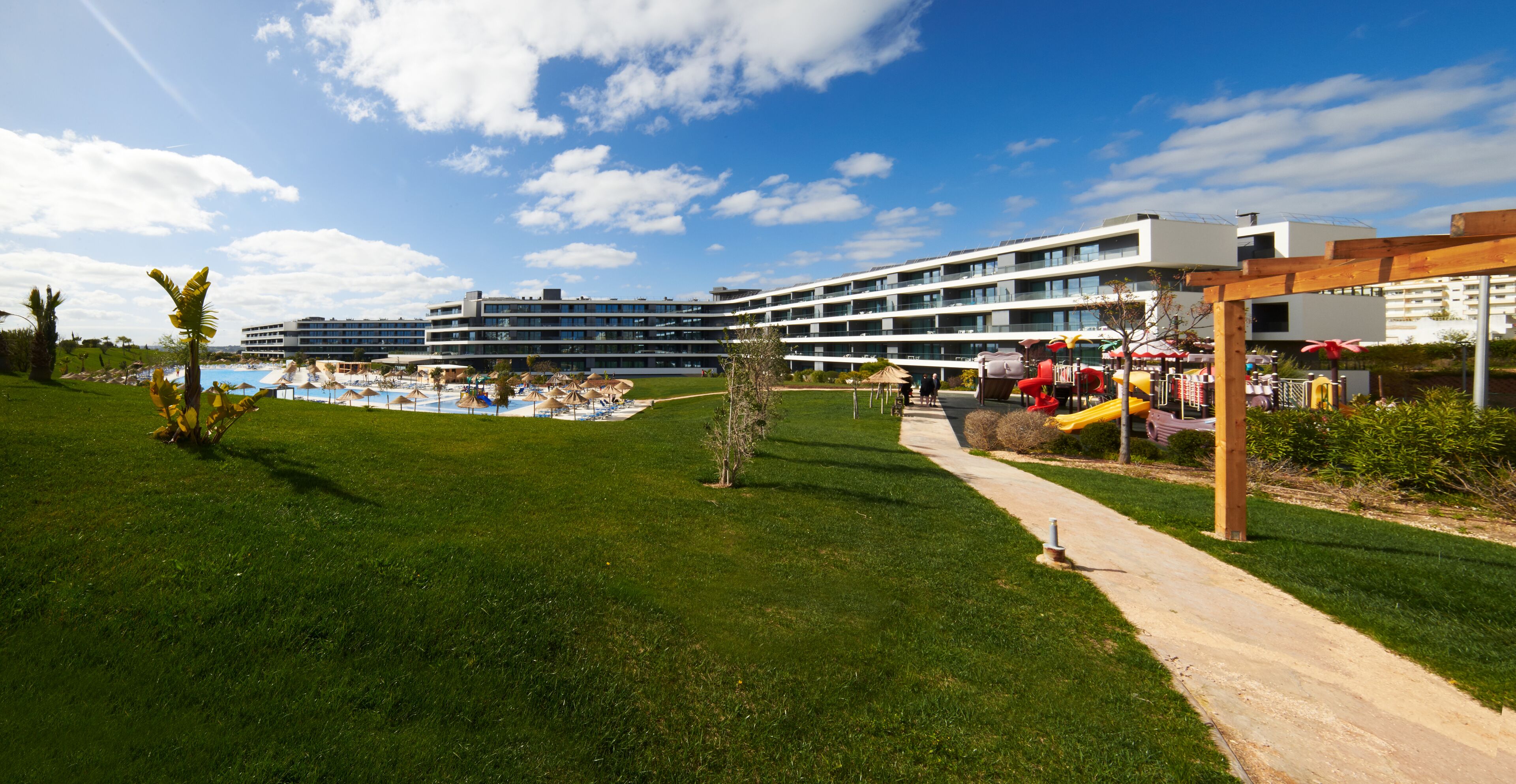 A hotel with a pool, outdoor seating, and a clear sky.