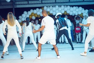 Un grupo de personas bailando en un espacio amplio con piso de baldosas.