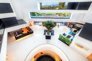 A spacious lobby with a central seating area, a reception desk, and a staircase leading to an upper level.