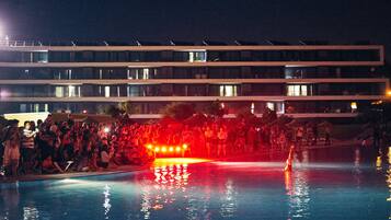 Una piscina con gente y un edificio al fondo.
