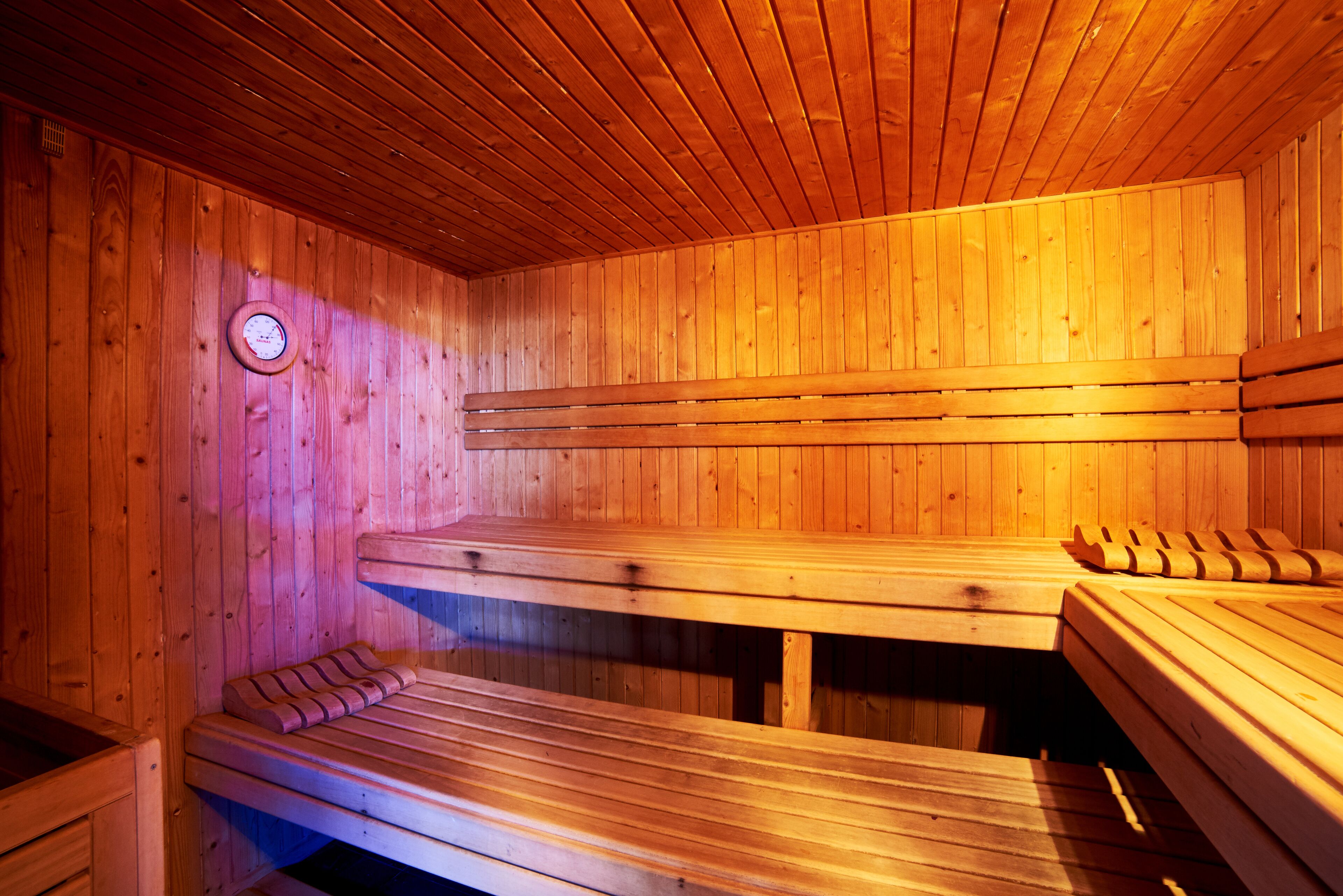 A sauna with wooden benches and a wall-mounted clock.