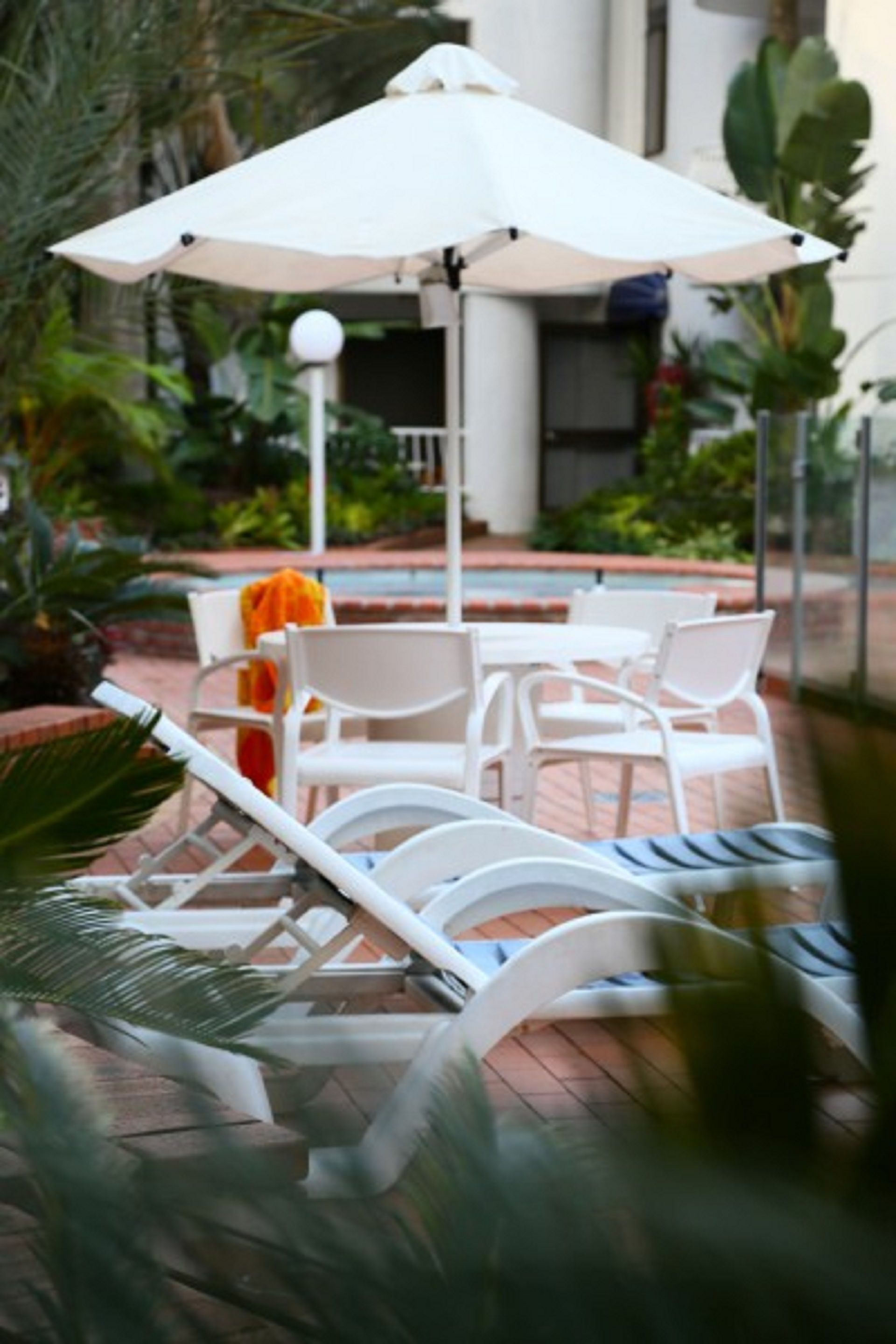 A patio area with white lounge chairs and a large white umbrella.