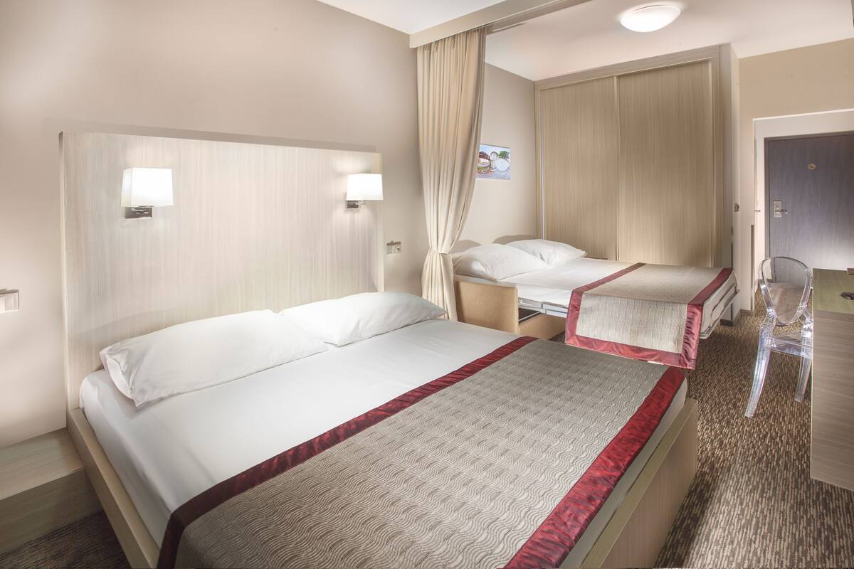 A hotel room with two beds, a desk, and a chair.