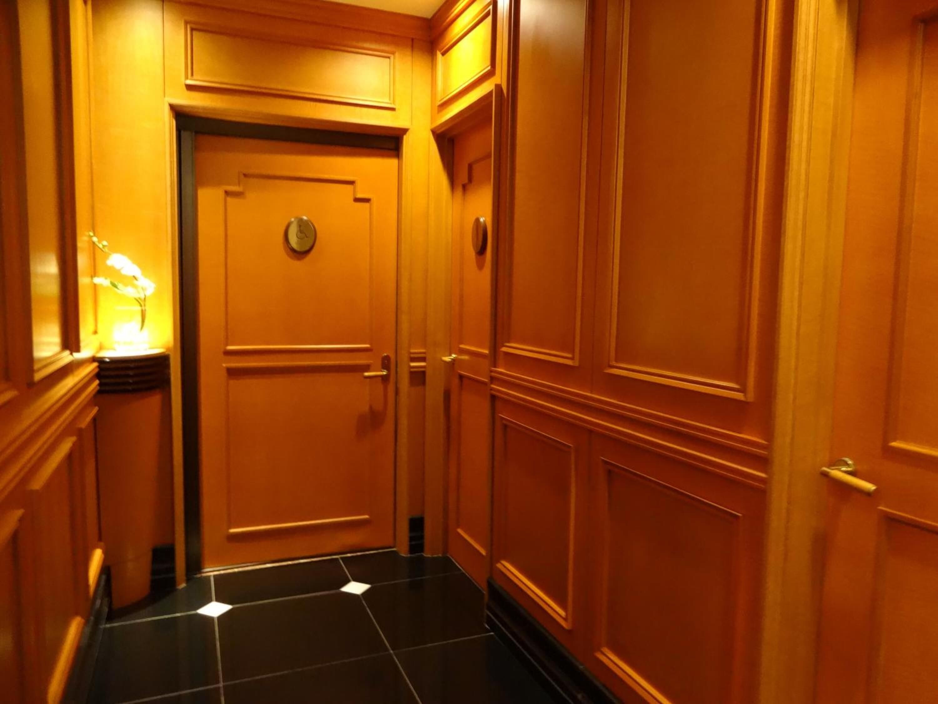 A hallway with wooden paneling and a black tiled floor.
