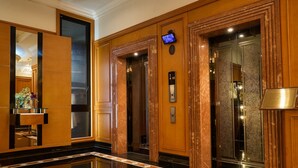 A hotel lobby with a polished black floor, wooden paneling, and two elevators. - Hotel Blion Naha (Naha)
