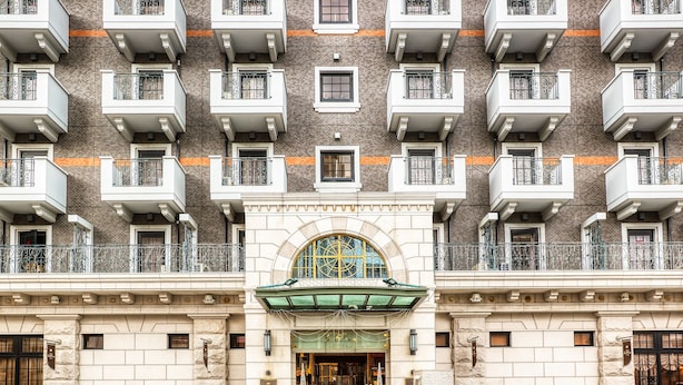A multi-story building with a central entrance featuring a green awning and a decorative glass window. - Hotel Blion Naha (Naha)