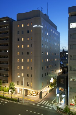 Um hotel com vários andares e um destaque para a placa "ABORA PLACE", apresentando um design arquitetônico moderno com telhado plano e várias janelas.