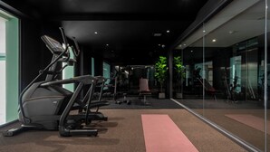 A gym with exercise equipment, a large mirror, and a carpeted floor. - Myhotel CMYK Ratchada (Bangkok)
