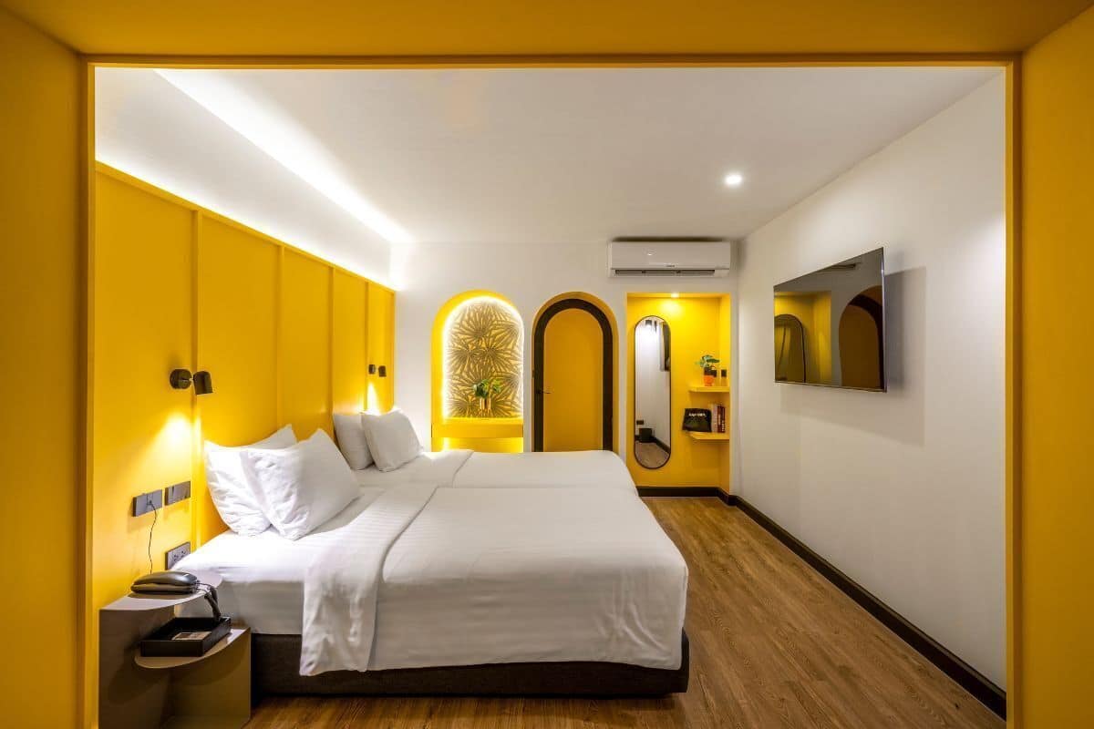 A modern hotel room with a large bed, bedside tables, a TV, and a mirror.
