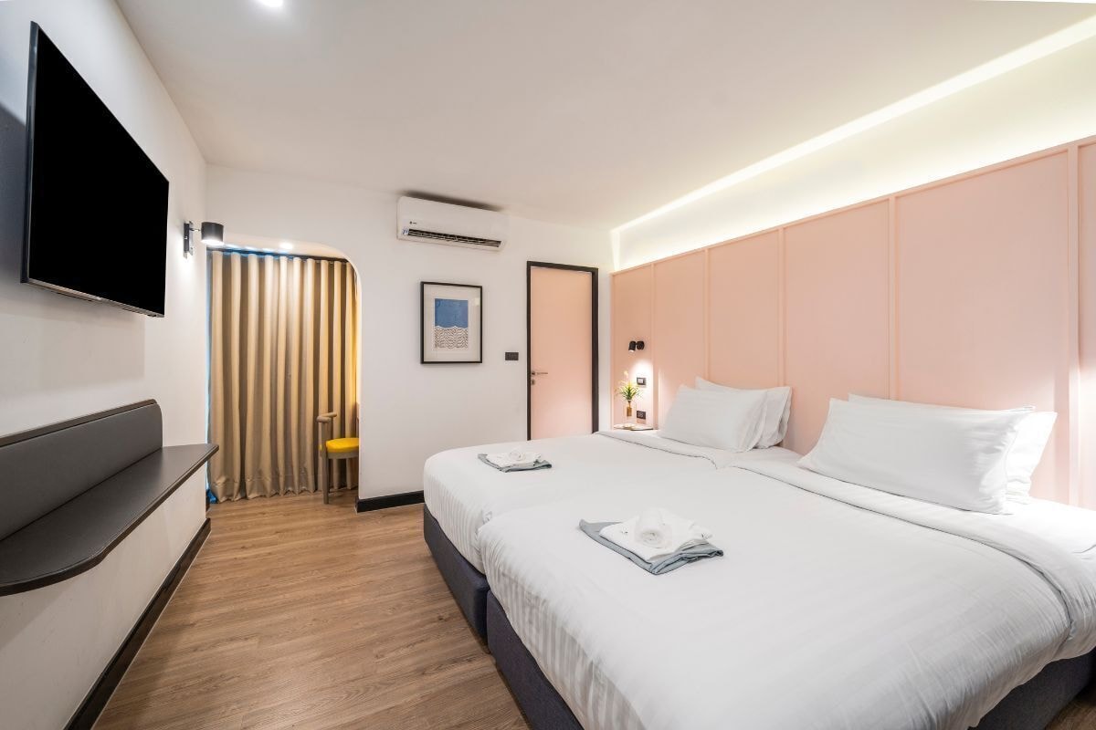 Una habitación de hotel con cama, televisor montado en la pared, escritorio y silla.
